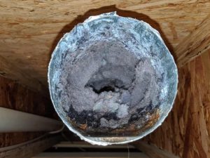 Picture looking into a completely clogged dryer vent duct that was disconnected in the ceiling to get better access for cleaning.