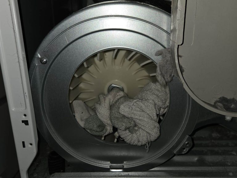 Dryer repair to fix dryer not starting properly. Picture of Dryer fan with a sock stuck in it.